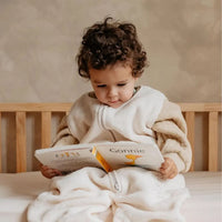 baby in slaapzak leest boekje